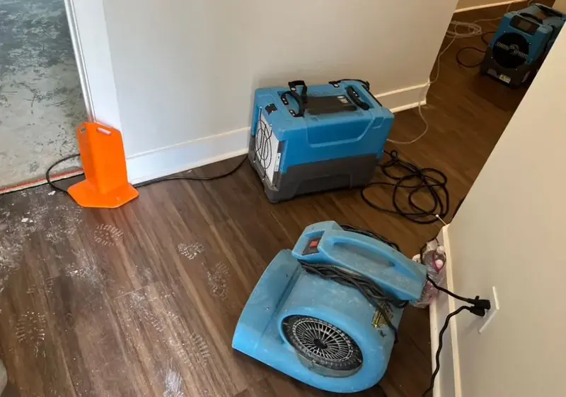 Air movers and a dehumidifier drying a room after water damage in Cypress, TX